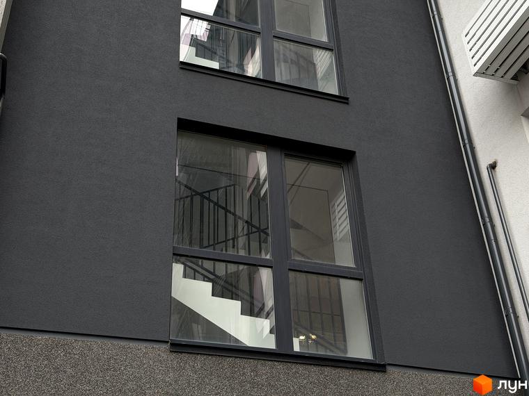 Фасад житлового комплексу Park Residence з великими вікнами та сходами всередині. Вид на прибудинкову територію з сучасним оформленням.