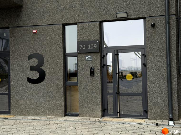 Вхід до будинку номер 3 житлового комплексу Park Residence з великими вікнами та сучасними елементами. Прибудинкова територія викладена плиткою.