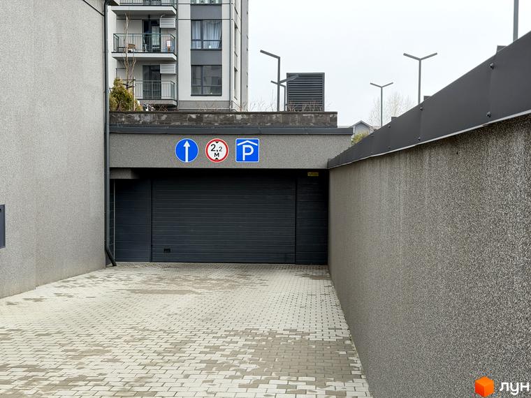 В'їзна зона підземного паркінгу житлового комплексу Park Residence з плитковим покриттям та дорожніми знаками.