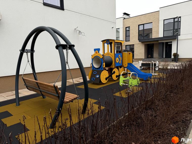 Сучасний будинок житлового комплексу Таунхауси Soul City з ігровим майданчиком та лавкою на прибудинковій території.