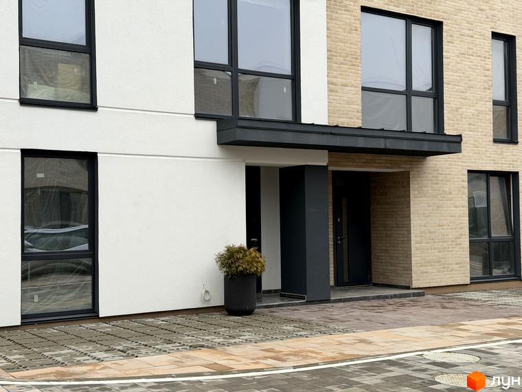 Фасад таунхаусів Soul City з великими вікнами та сучасним оформленням. Прибудинкова територія з плиткою та зеленими насадженнями.
