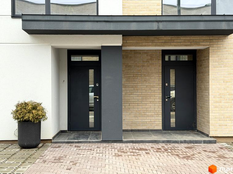 Вхідна група таунхаусів Soul City з чорними дверима та цегляною стіною. Прибудинкова територія викладена плиткою з зеленими насадженнями.