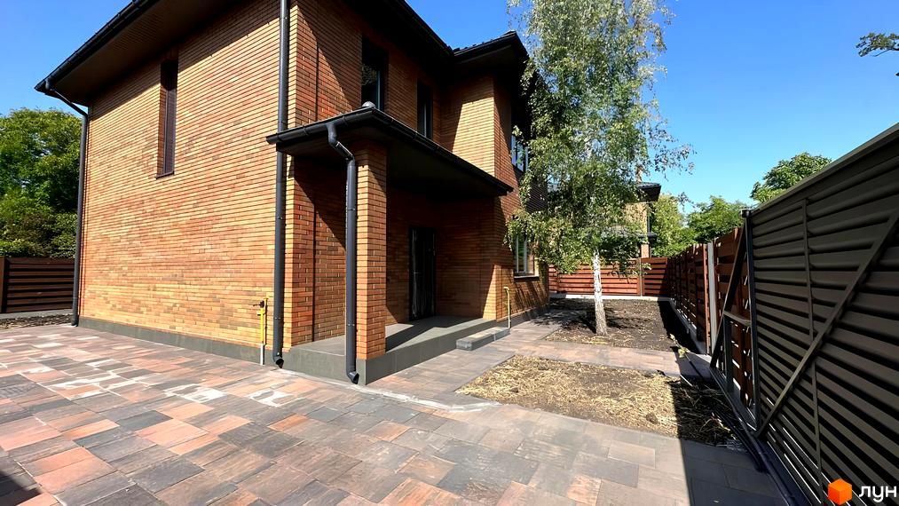 Зовнішній вигляд будинку КМ Villa Lisova з червоної цегли та прибудинкова територія з озелененням.