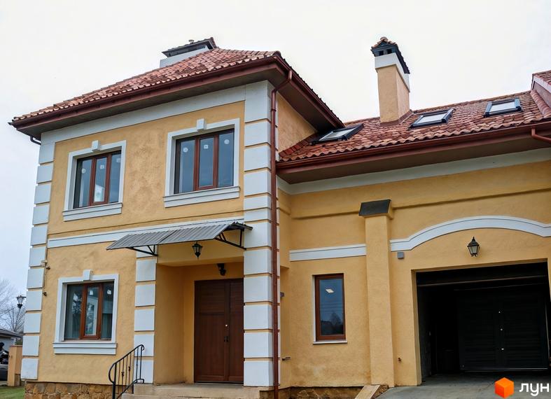 Зовнішній вигляд будинку житлового комплексу КМ Монастирський з жовтою фасадною штукатуркою та червоною дахівкою.