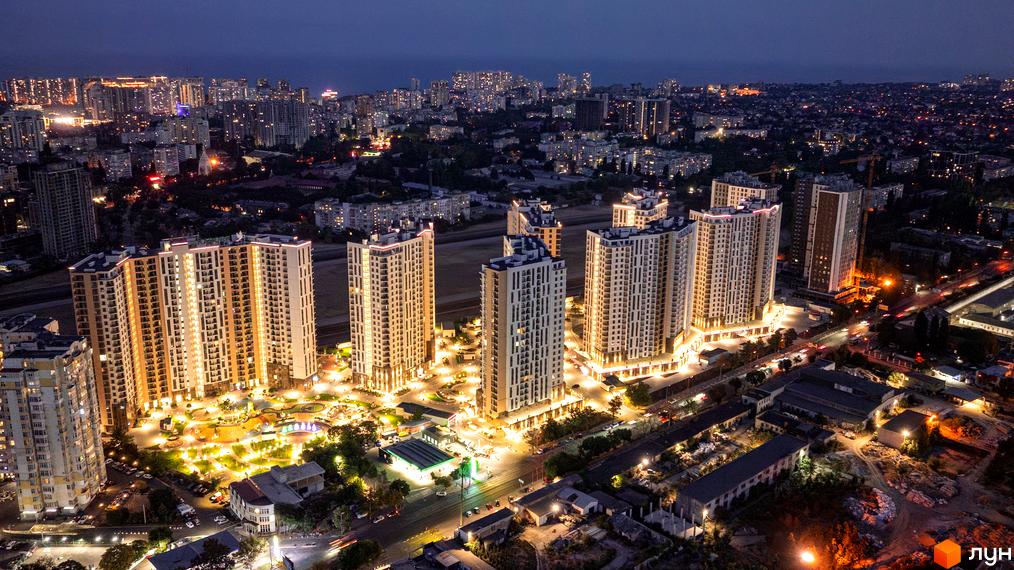 Житловий комплекс KADORR City з висотними будинками та прибудинковою територією, освітленою вночі.