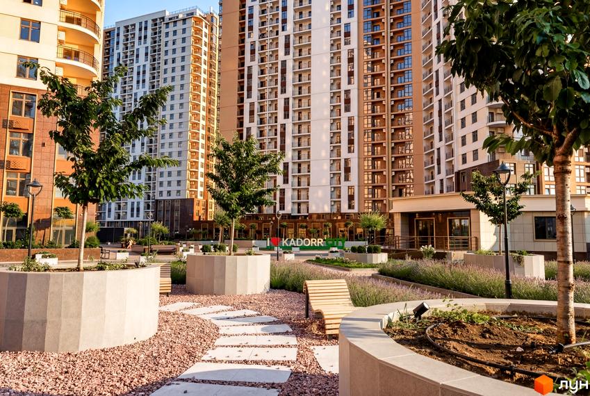 Житловий комплекс KADORR City з сучасними багатоповерхівками та облаштованою прибудинковою територією з зеленими насадженнями.