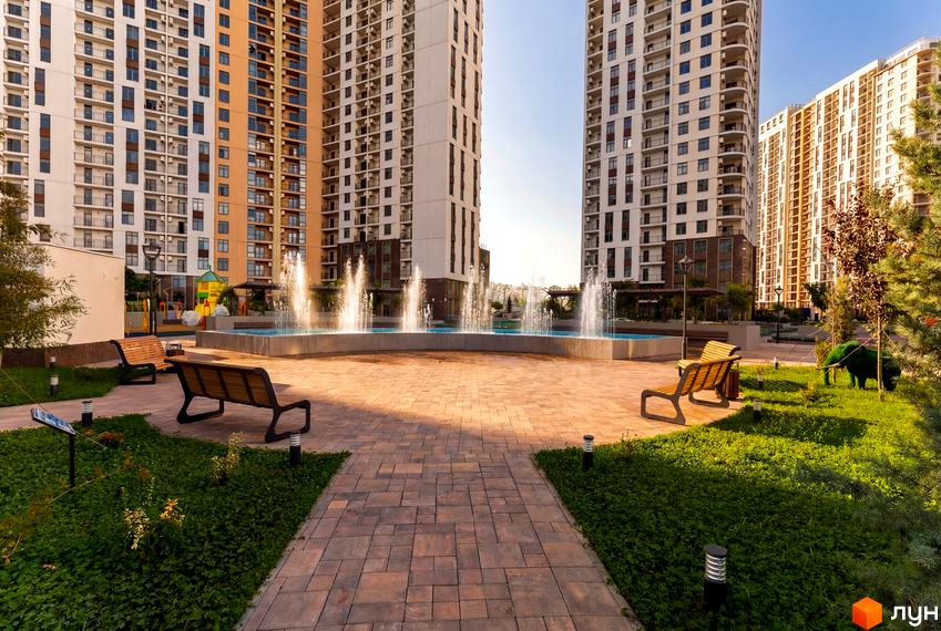 Житловий комплекс KADORR City з сучасними будинками та прибудинковою територією з фонтаном і зеленими насадженнями.