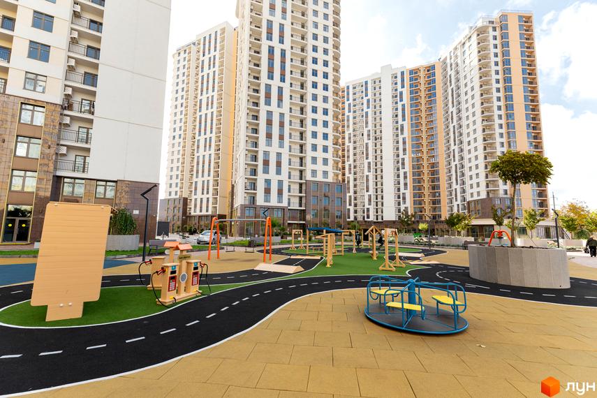 Житловий комплекс KADORR City з сучасними будинками та облаштованою прибудинковою територією з дитячим майданчиком.