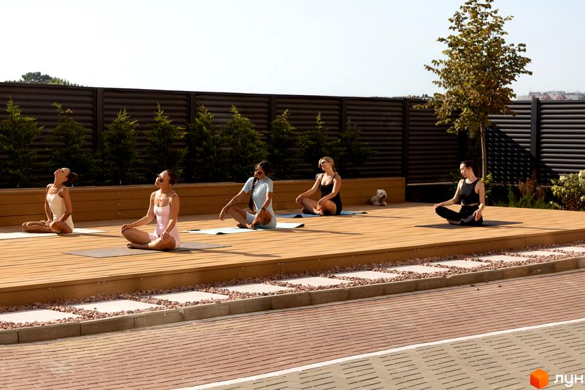 Зовнішній вигляд території житлового комплексу KADORR City з йога-платформою та зеленими насадженнями.