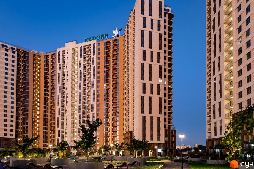 Житловий комплекс KADORR City з сучасними фасадами та прибудинковою територією, озелененою деревами та ліхтарями.