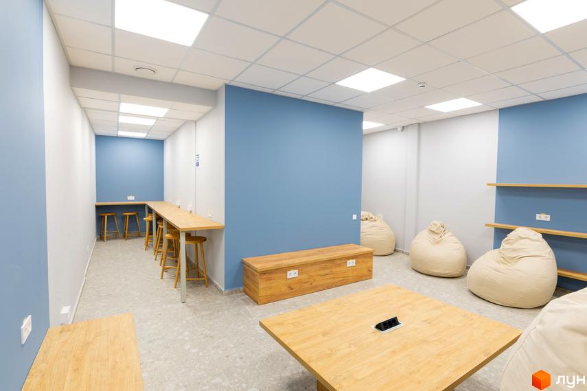 Сучасний інтер'єр спільного простору житлового комплексу KADORR City з дерев'яними меблями та м'якими пуфами.