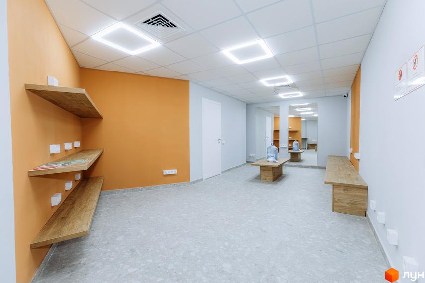 Сучасний інтер'єр приміщення житлового комплексу KADORR City з дерев'яними полицями та світлими стінами.