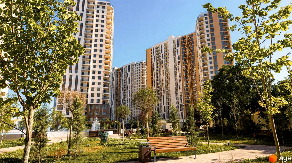 Житловий комплекс KADORR City з сучасними багатоповерхівками та зеленими прибудинковими територіями. На фоні видно дерева та зони відпочинку.