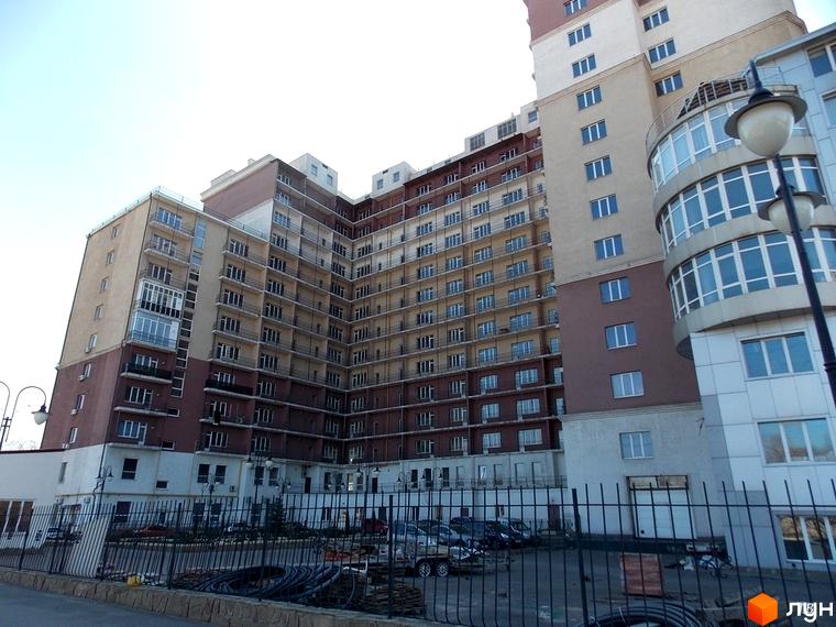 Багатоповерхова новобудова ЖК Лермонтово з балконами та скляними фасадами. На передньому плані парковка та металева огорожа.