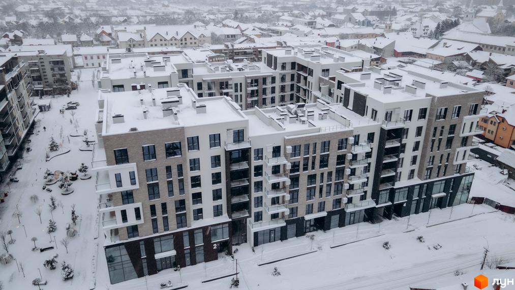Житловий комплекс SKY CITY з сучасними фасадами, оточений засніженою прибудинковою територією та зеленими насадженнями.