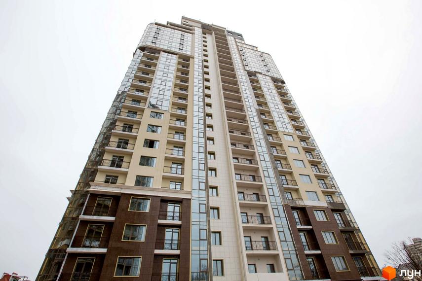 Високоповерховий житловий комплекс Сьома Перлина з панорамним склінням та балконами. Зовнішній вигляд новобудови з бежевим та коричневим фасадом.