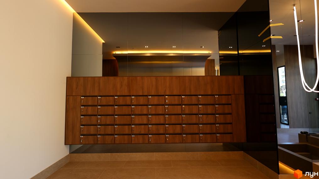 Вхідна зона житлового комплексу SKY CITY з поштовими скриньками та сучасним освітленням. Просторий інтер'єр з елементами дерева та скла.