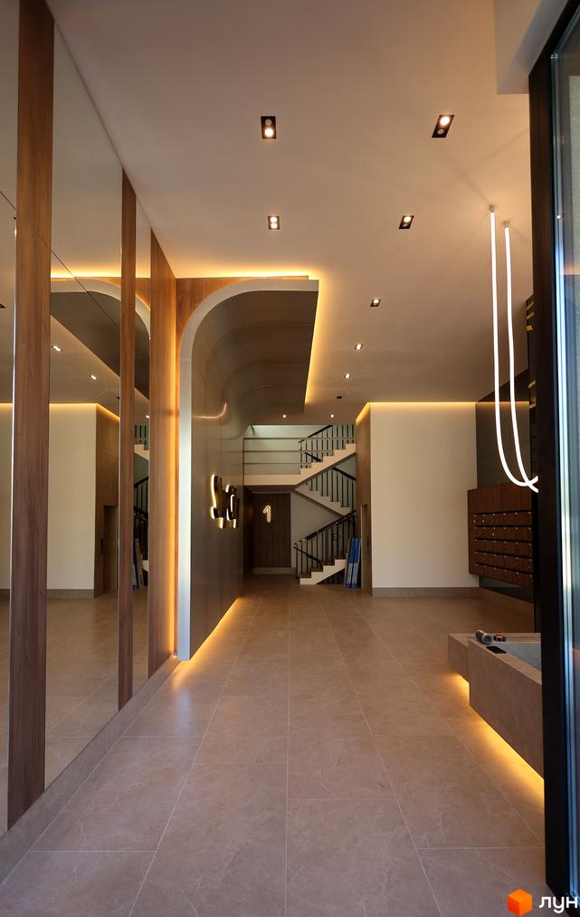 Внутрішній вигляд житлового комплексу ЖК SKY CITY з сучасними елементами дизайну та освітленням. Вид на сходи та зону рецепції.