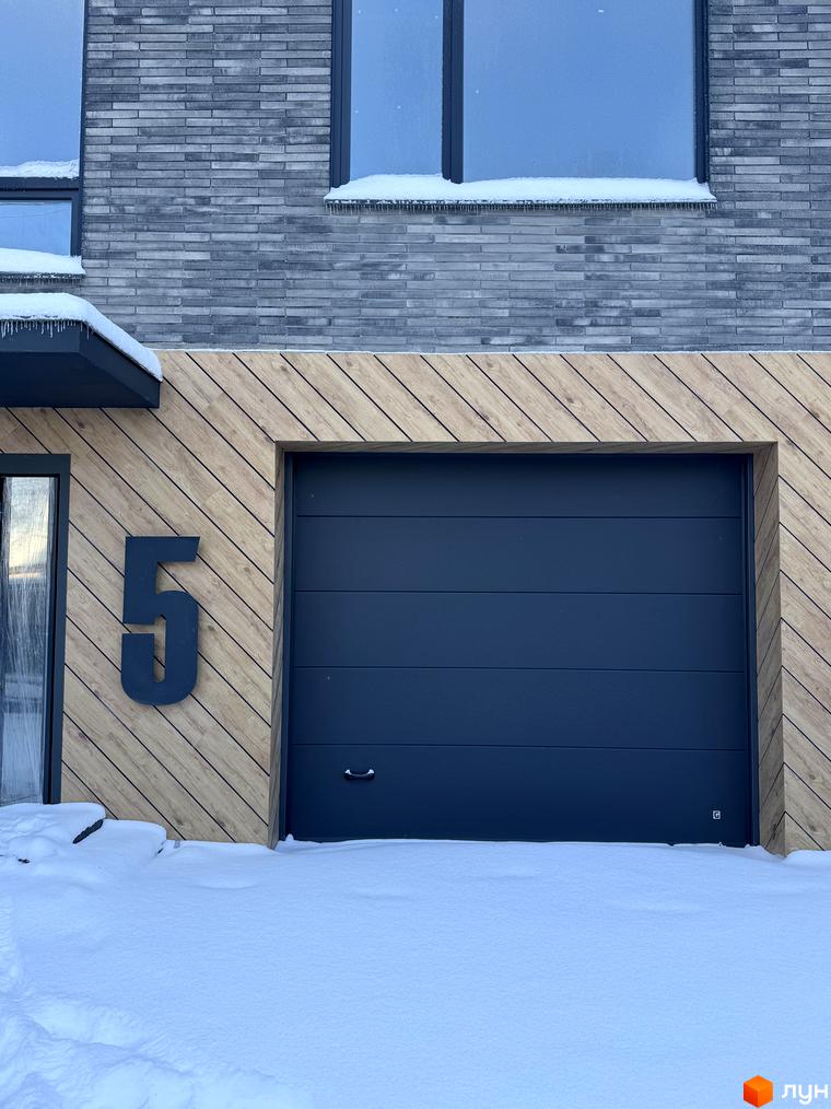 Фасад Таунхаусів Madera House з великими вікнами та дерев'яними елементами. Прибудинкова територія засипана снігом.