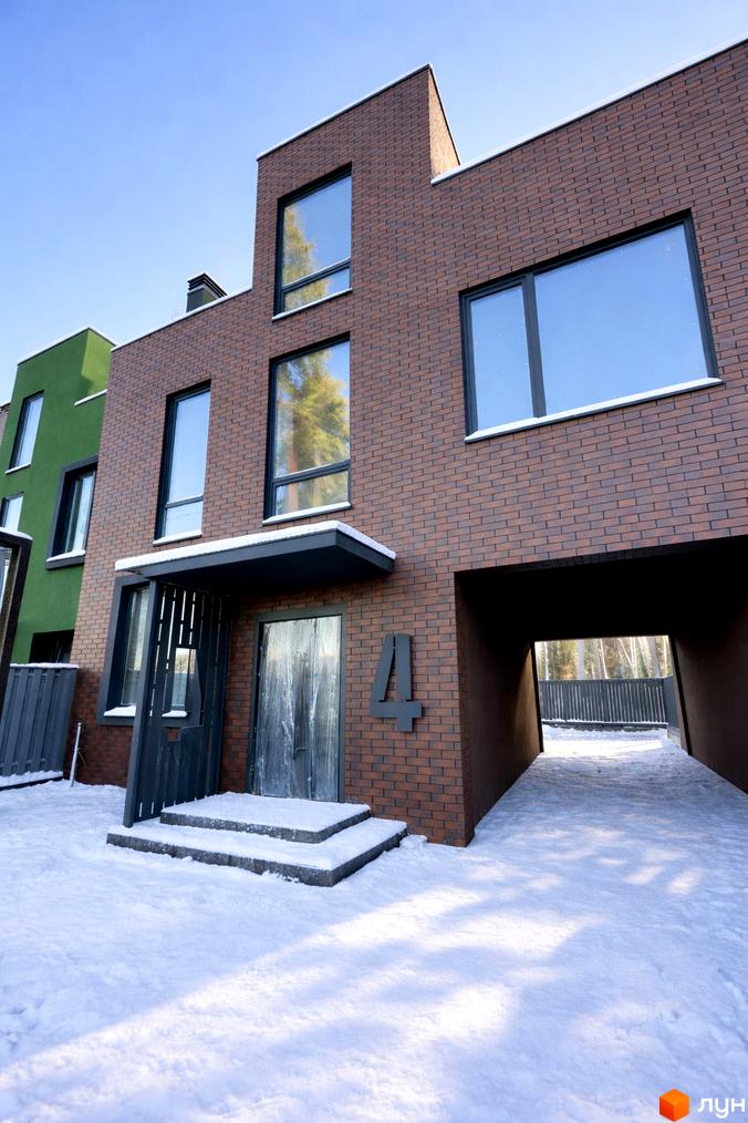 Фасад таунхаусу Madera House з цегляною обробкою та великими вікнами. Прибудинкова територія засипана снігом.