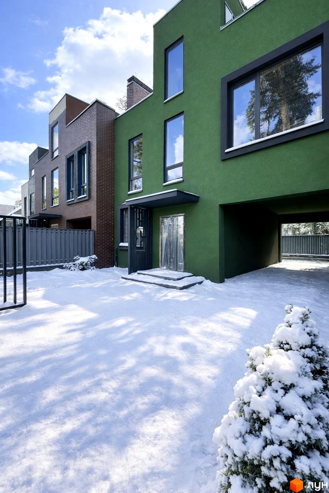 Зовнішній вигляд Таунхаусів Madera House з зеленими фасадами та прибудинковою територією, засніженою та облаштованою рослинами.