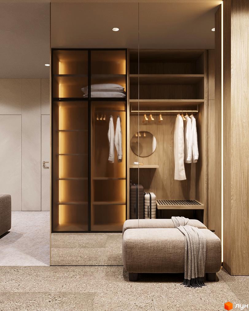 Інтер'єр житлового комплексу Logos Home Apartment з шафою та м'яким пуфом. Світле приміщення з дерев'яними елементами.