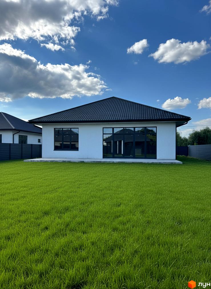 Зовнішній вигляд будинку КМ Котеджі на Київській з великими вікнами та зеленою прибудинковою територією.