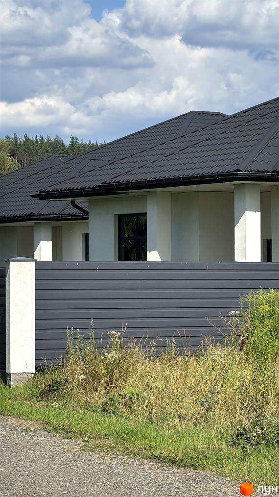 Зовнішній вигляд котеджного комплексу КМ Котеджі на Київській, з сучасним дахом та прибудинковою територією з травою.