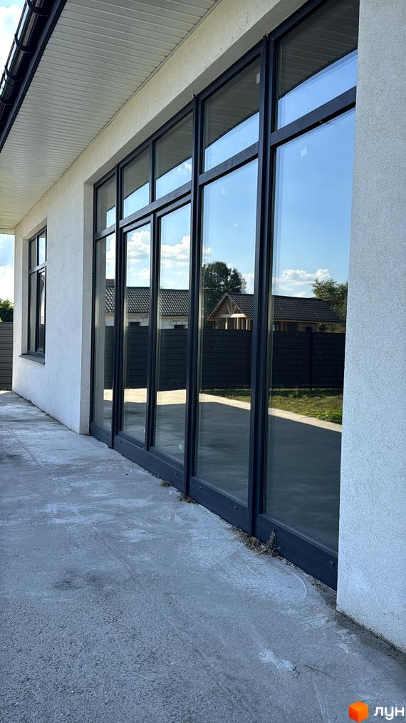 Зовнішній вигляд будинку КМ Котеджі на Київській з великими вікнами. Прибудинкова територія з рівною поверхнею та огорожею.