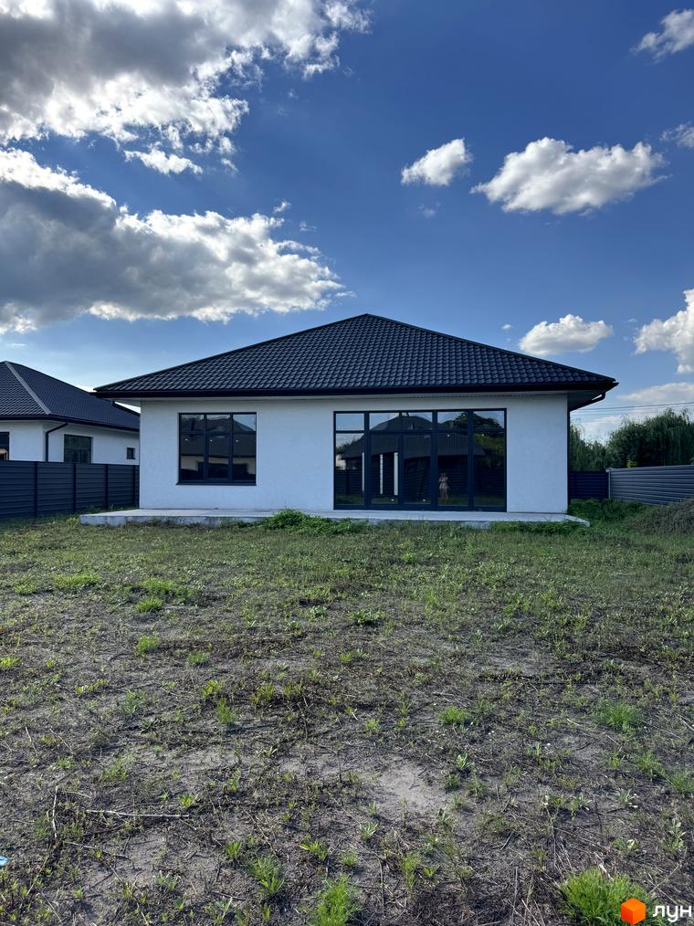 Будинок у житловому комплексі КМ Котеджі на Київській з великими вікнами та плоским дахом, оточений прибудинковою територією.