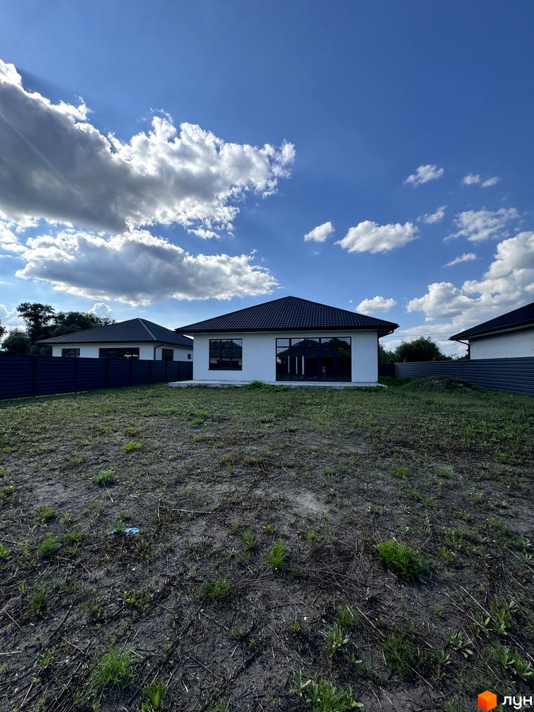 Зовнішній вигляд котеджу в житловому комплексі КМ Котеджі на Київській з прибудинковою територією та зеленими насадженнями.