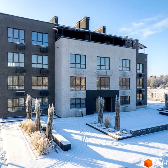 Зовнішній вигляд будинку ЖК FAMILY PARK APARTMENS з великими вікнами. Прибудинкова територія з зеленими насадженнями та засніженим ландшафтом.