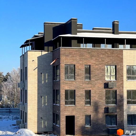 Житловий комплекс FAMILY PARK APARTMENS з сучасним фасадом. Прибудинкова територія з зеленими насадженнями та снігом.