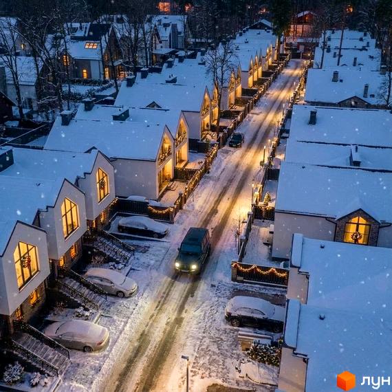 Зовнішній вигляд котеджного містечка КМ Park Residence 3 в зимовий період, освітлені будинки та засніжені вулиці.