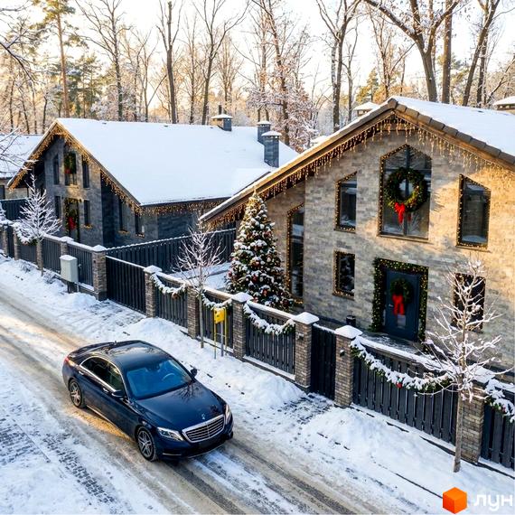 Зовнішній вигляд будинків житлового комплексу КМ Park Residence 3, прикрашених до свят. Приблизно зимова обстановка з автомобілем на засніженій дорозі.