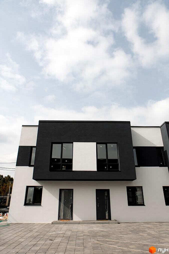 Зовнішній вигляд таунхаусів SDG BILOHORODKA 2 з чорними та білими фасадами. Прибудинкова територія з плиткою та облаштуванням.