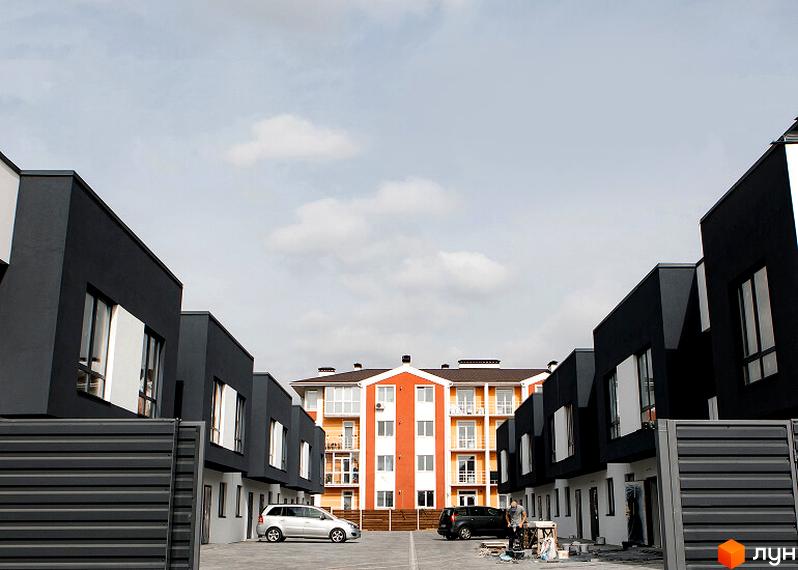 Житловий комплекс Таунхауси SDG BILOHORODKA 2 з сучасними та просторими будинками. Прибудинкова територія з паркувальними місцями та зеленими насадженнями.