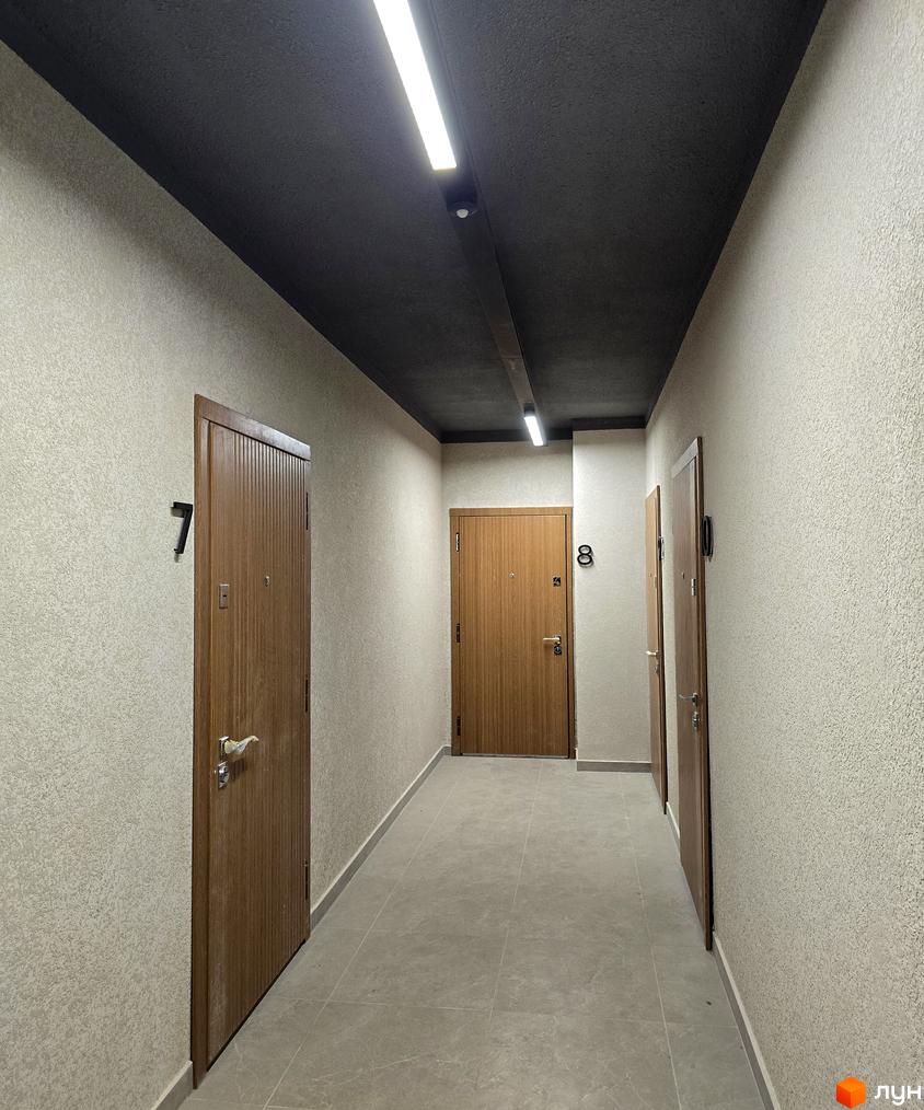 Коридор житлового комплексу ЖК КОРОНА з дверима квартир та освітленням. Сучасна обробка стін та підлоги.