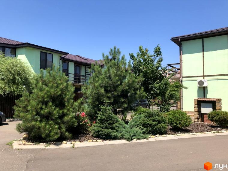 Зовнішній вигляд житлового комплексу КМ Академічний з зеленими насадженнями та прибудинковою територією.