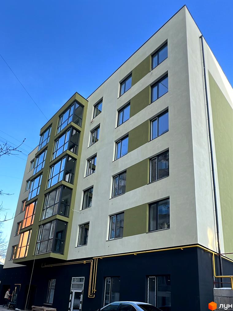 Фасад новобудови на вул. Заболотного з великими вікнами та комбінованим оздобленням стін. Будівельний проєкт з сучасною архітектурою.