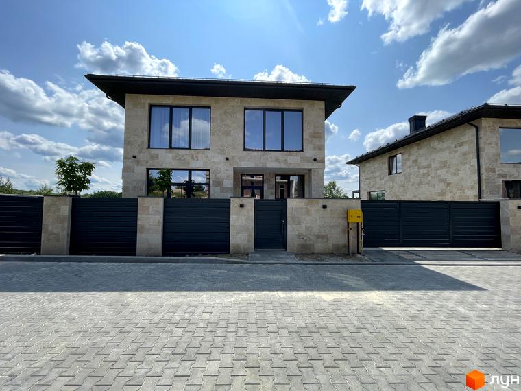 Будинок житлового комплексу КМ Нова Ходосівка з великими вікнами та сучасним фасадом. Прибудинкова територія з паркувальними місцями та зеленими насадженнями.