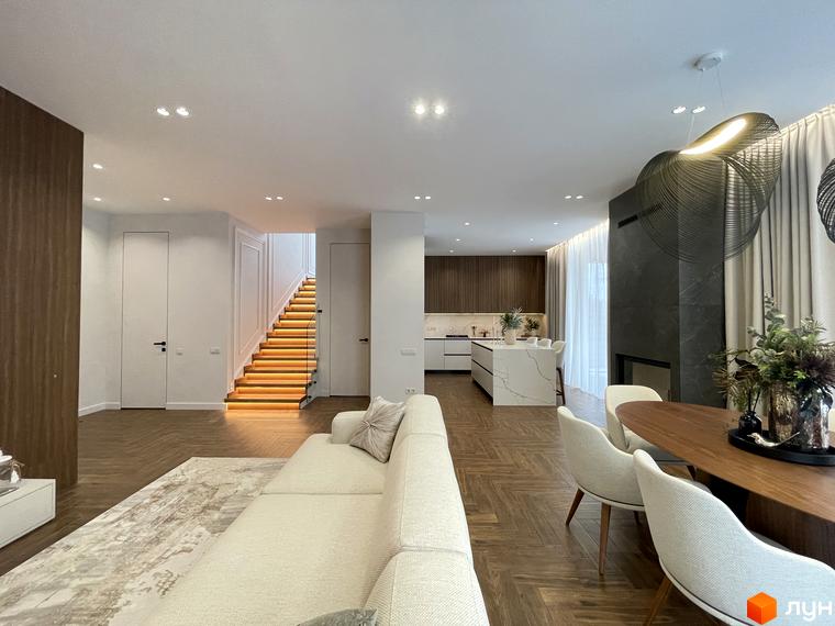 Сучасний інтер'єр будинку в КМ Нова Ходосівка з кухнею та обідньою зоною. Світлі тони, дерев'яна підлога та сходи з підсвіткою.