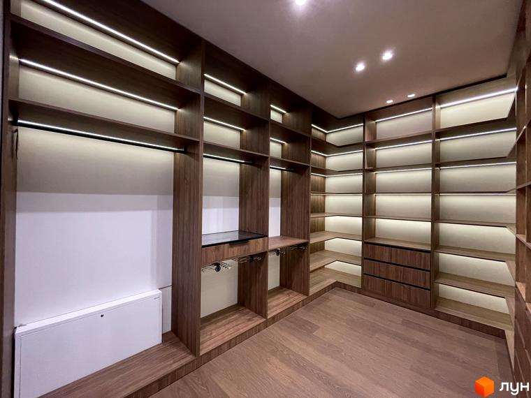 Сучасний інтер'єр кімнати для зберігання з дерев'яними полицями та освітленням. Простора зона для організації речей.