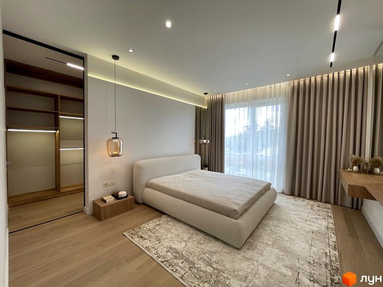 Сучасна спальня в житловому комплексі КМ Нова Ходосівка з великим вікном та зручним ліжком. Прибудинкова територія оформлена з урахуванням комфорту мешканців.