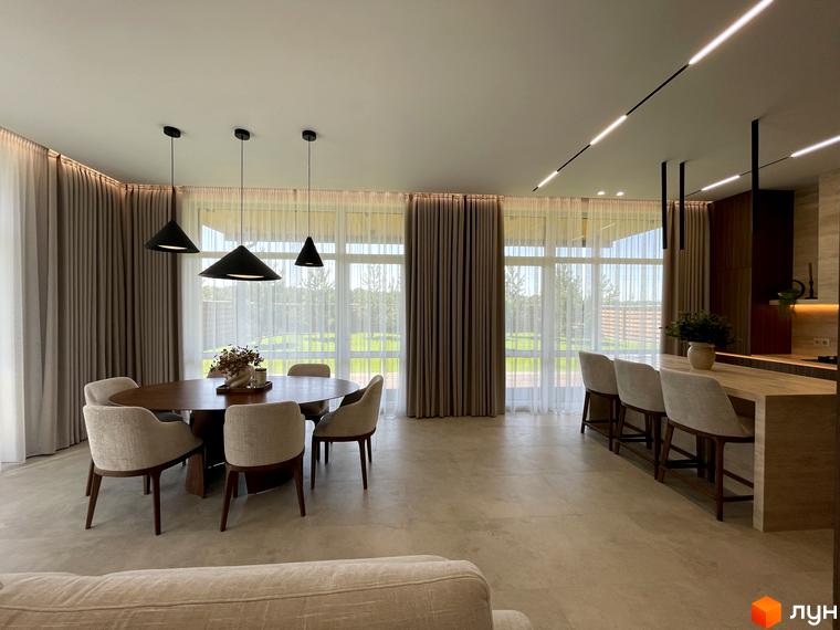 Сучасний інтер'єр житлового комплексу КМ Нова Ходосівка з обіднім столом та кухнею. Вікна виходять на прибудинкову територію з зеленими насадженнями.