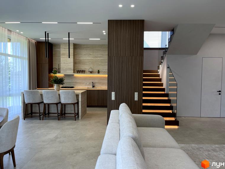 Сучасний інтер'єр будинку з кухнею та сходами. Приємна атмосфера та зручна зона для відпочинку.