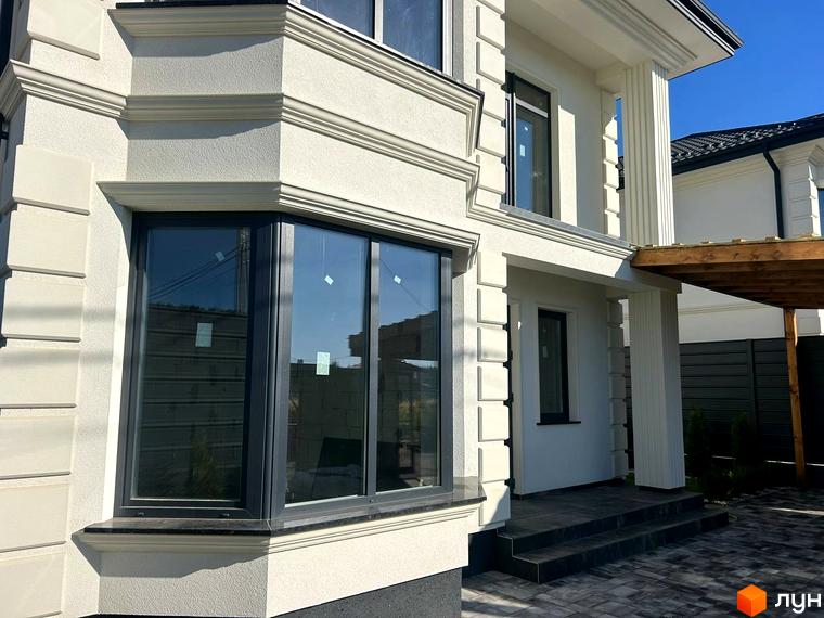 Зовнішній вигляд будинку комплексу Благовісний з великими вікнами та підходом до входу. Прибудинкова територія з плиткою та зеленими насадженнями.