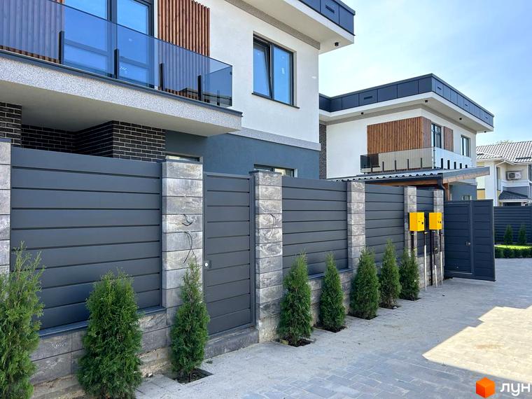 Зовнішній вигляд комплексу Прикордонний з сучасним фасадом та прибудинковою територією, обгородженою живою огорожею.