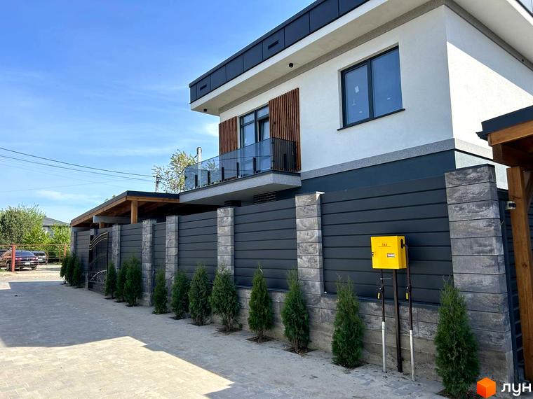 Зовнішній вигляд житлового комплексу Комплекс Прикордонний з сучасним фасадом та прибудинковою територією, озелененою хвойними рослинами.