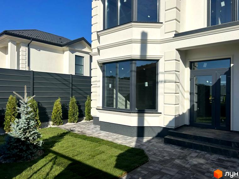 Зовнішній вигляд будинку Комплекс Благовісний з великими вікнами та прибудинковою територією, озелененою хвойними рослинами.